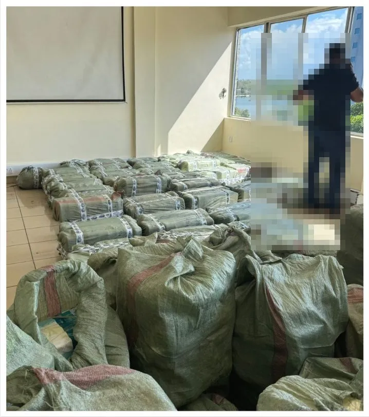 Sacks of seized narcotics stacked in a room in Tanzania; the officer present is pixelated